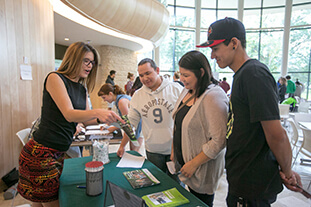 An employer talking to students at a career fair booth.